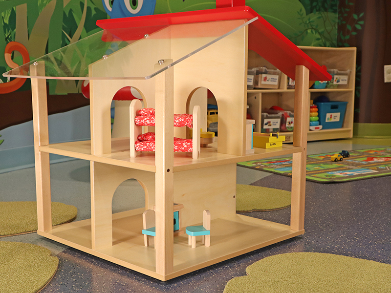 A wooden dollhouse with other toys in the background