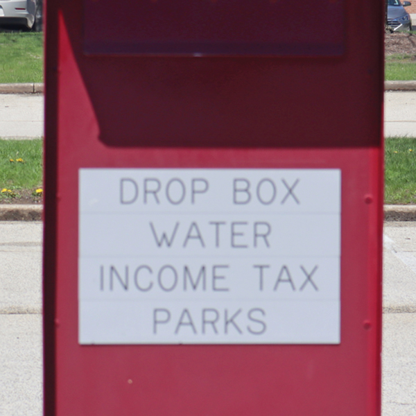 a red drop box with a sign that reads drop box, water, income tax, parks