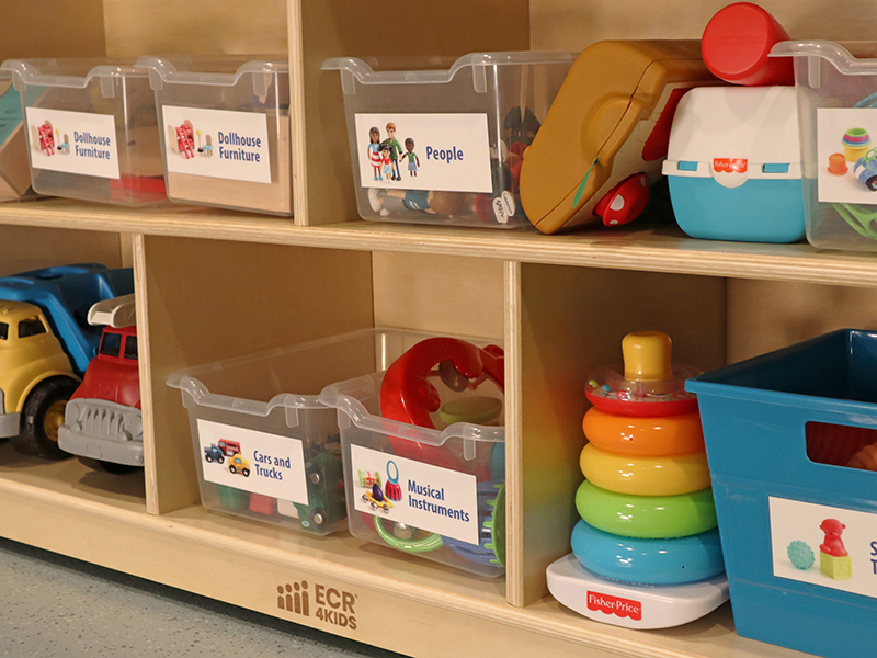 A book shelf full of toy bins