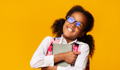 Little girl hugging a book against a yellow background